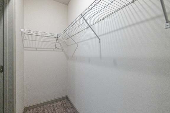A white walk in closet with a metal rack. at 1701 North Apartment Homes Apartments, North Carolina