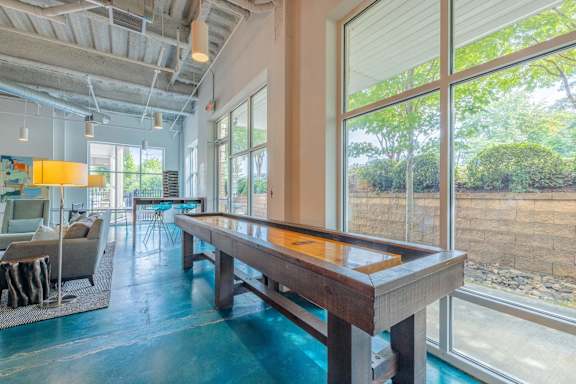 A pool table in a room with a view of a rocky landscape outside the window at 1701 North Apartment Homes Apartments, Chapel Hill, NC