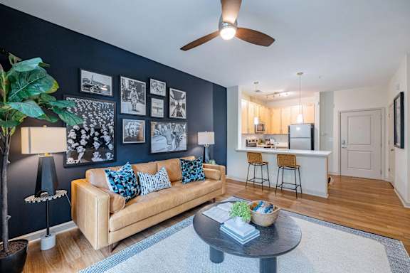 A living room with a beige couch and a ceiling fan. at 1701 North Apartment Homes Apartments, Chapel Hill, North Carolina