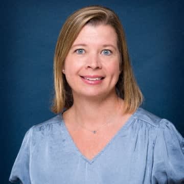 a woman in a blue shirt is posing for a picture