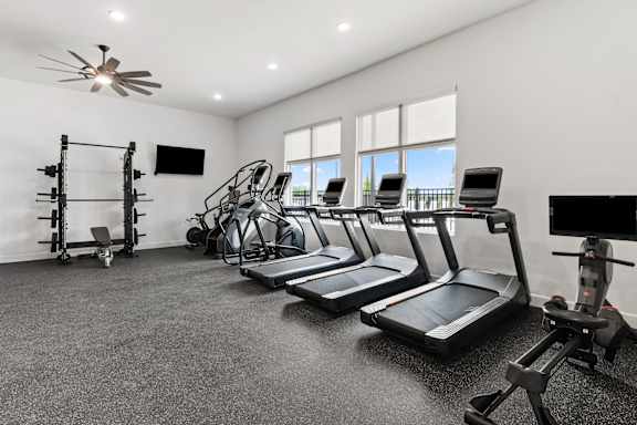 A spacious home gym with treadmills, a stationary bike, and a weight rack.