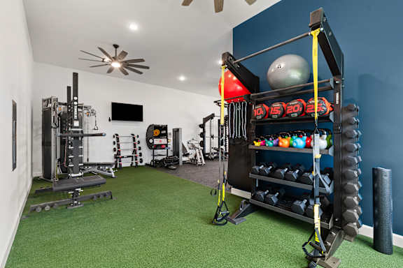 A home gym with a green carpet and various exercise equipment.