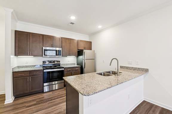 A kitchen with brown cabinets and a granite countertop  at Ardmore at the Trail, Indian Trail