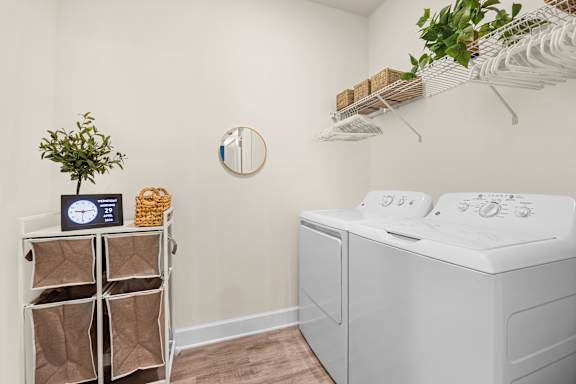 A laundry room with a washing machine and a shelf with bags and a plant.