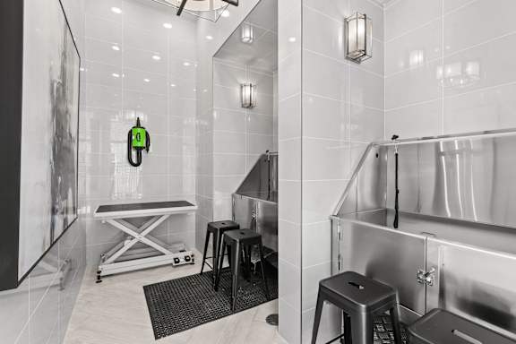 A bathroom with a white tiled wall and a black and white photo on the wall.