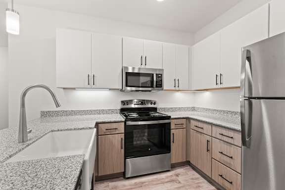 A modern kitchen with a stainless steel refrigerator, microwave, and oven.