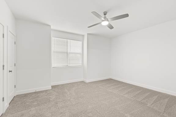 A room with a ceiling fan and carpeted floor.