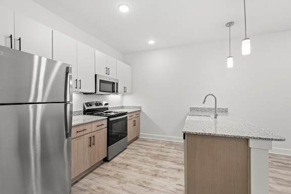 A kitchen with a stainless steel refrigerator, microwave, oven, and sink.