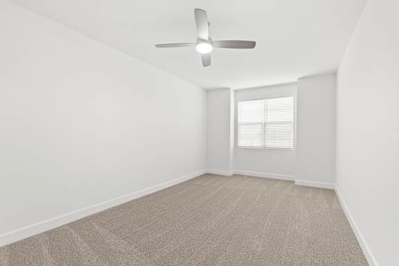 A room with a ceiling fan and carpeted floor.