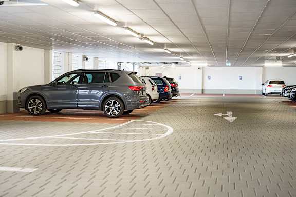 A parking garage with a grey car in the foreground.