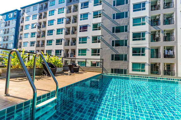 A swimming pool in front of a multi-story residential building.
