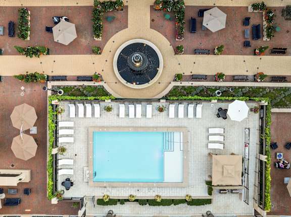 A pool surrounded by a patio with chairs and plants at Sophia Square Apartments, Indiana