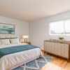 A bedroom with a bed, nightstand, and a painting on the wall.