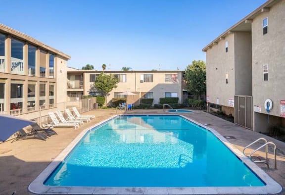 a swimming pool with chaise lounge chairs and a building in the background at Mountainview Venture, Covina, CA