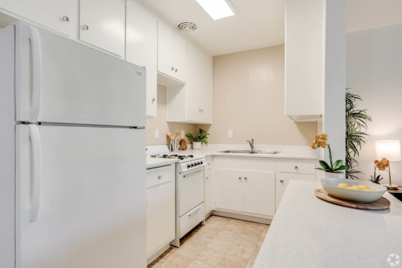 a white kitchen with white cabinets and a white refrigerator at University Park, Azusa, CA 91702