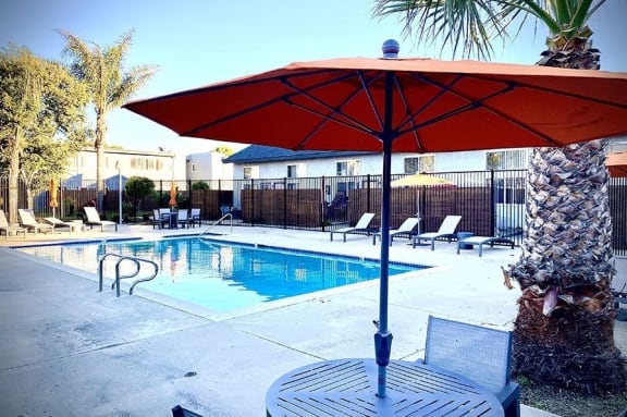 a swimming pool with a table and umbrella at Fiesta Apts, Lompoc, CA 93436