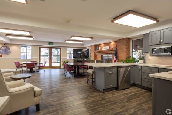 a clubhouse with a kitchen and a living room with a table and chairs at Huntington Terrace North Senior, Huntington Beach