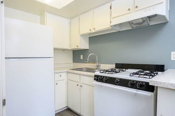 a kitchen with white cabinets and a white stove top oven at Sagewood Gardens Senior Apartments, Hacienda Heights
