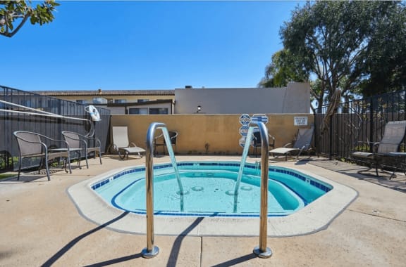 our resort style hot tub is next to our patio with chairs and a fence at Huntington Terrace North Senior, Huntington Beach, CA