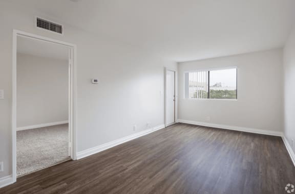 an empty living room with white walls and wood flooring at Huntington Terrace North Senior, Huntington Beach, 92648