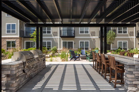 a covered patio with a grill and a table with chairs