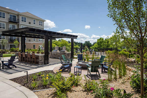 A patio with a table and chairs under a black pergola.
