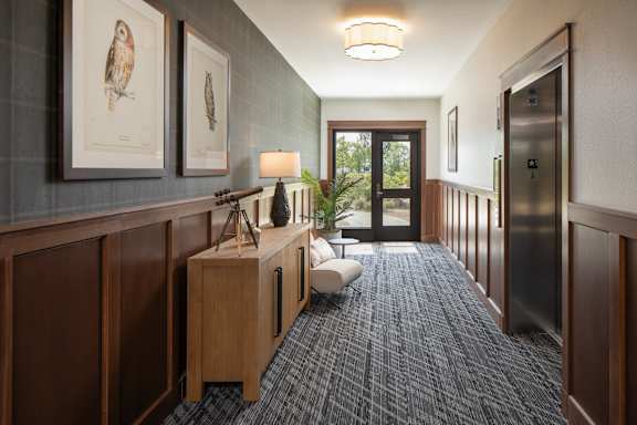 A hallway with a bench, lamp, and pictures on the wall.