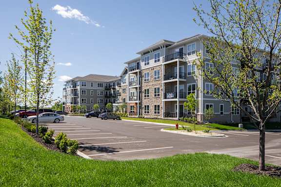 A parking lot in front of a large apartment building.