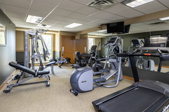 A gym with a variety of equipment including treadmills, elliptical machines, and weight machines.