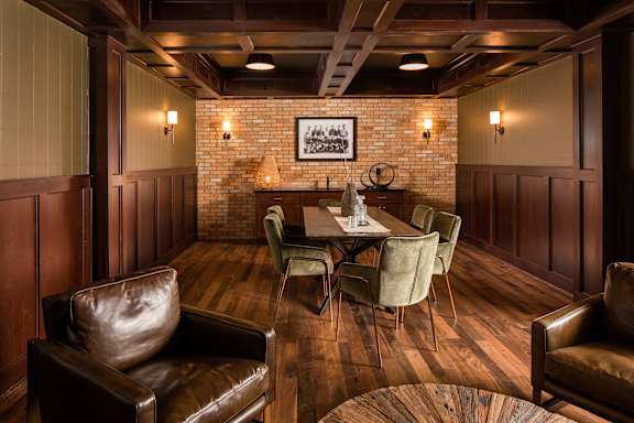 A room with brown leather chairs and a wooden table.