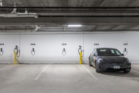 a tesla car parked in a parking garage next to a charging stationat The Carver Apartments, Minnesota