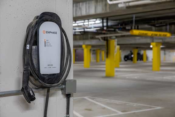 A black Enphase Energy power cable is hanging on a wall.