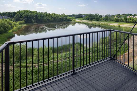 A balcony overlooks a river and greenery.