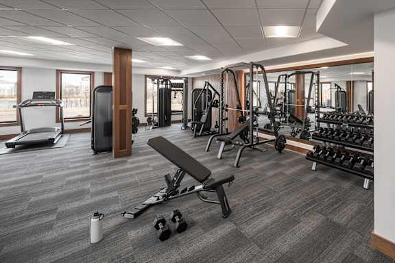 A gym with a variety of equipment including weights and a bench.