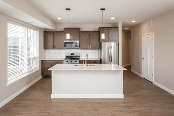 A modern kitchen with a white island and wooden cabinets.