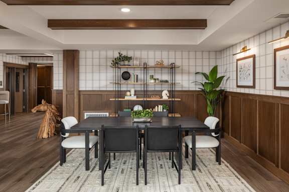 A dining room with a black table and chairs.