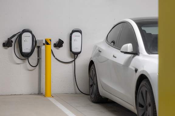 A white car is charging at a yellow charging station.