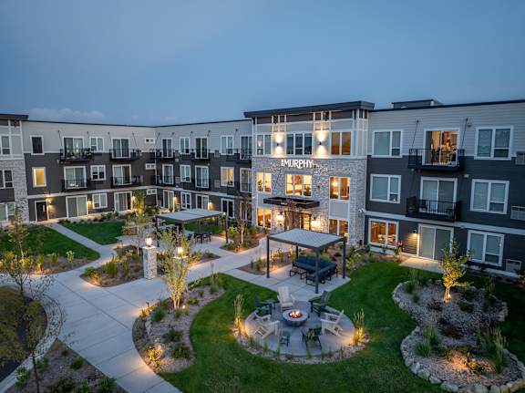 A courtyard with a fire pit surrounded by apartment buildings at dusk.
