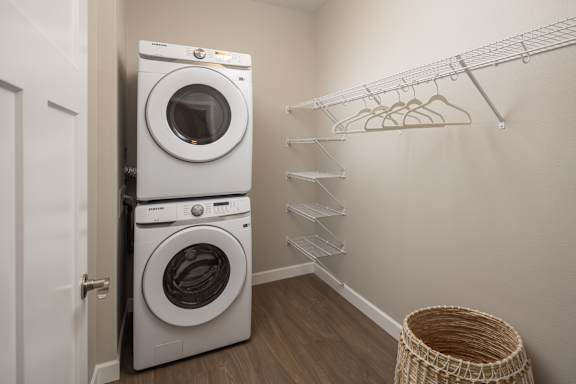 A laundry room with a white dryer and washer, a clothes rack and a basket.