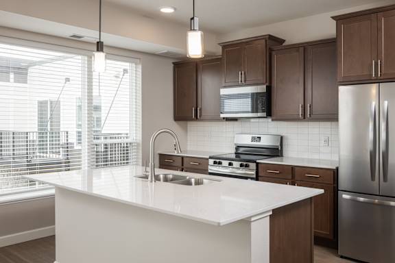 A modern kitchen with a white countertop and stainless steel appliances.