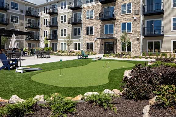 A small putting green is surrounded by apartment buildings.