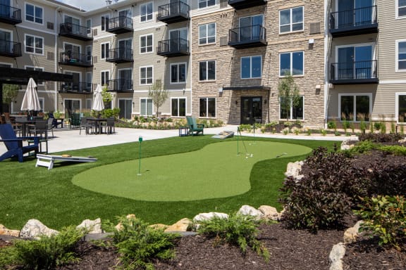 an artificial turf putting green in front of an apartment building