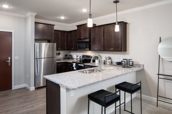 a kitchen with a large island with two stools in front of itat The Carver Apartments, Minnesota, 55318