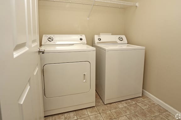 Two white front loading washing machines in a small laundry room.
