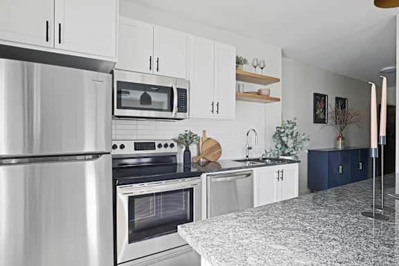 A modern kitchen with a refrigerator, oven, microwave, and sink.