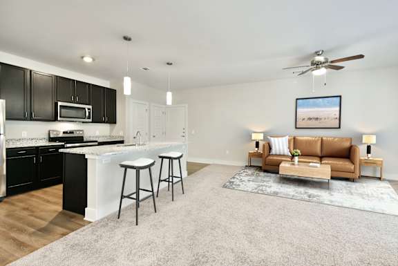 A modern kitchen with a bar area and a living room area with a couch.