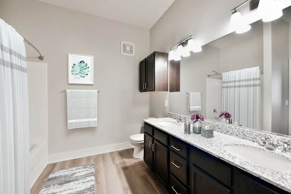 A bathroom with a white sink and brown cabinets.
