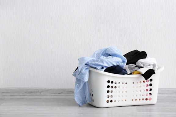 A white laundry basket filled with clothes.