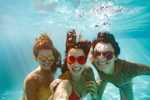 three women underwater in a swimming pool