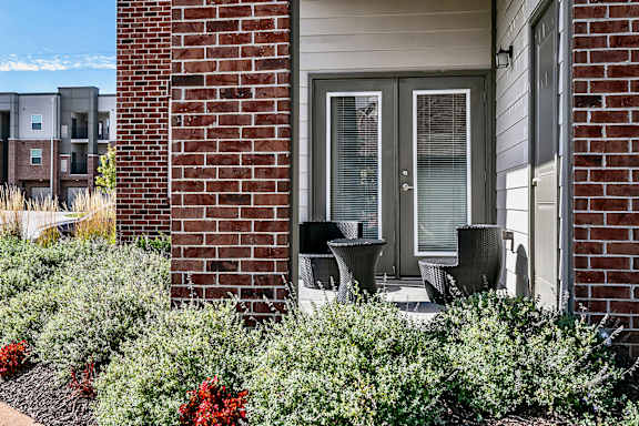 Outdoor patio with a glass door and a small garden in front.